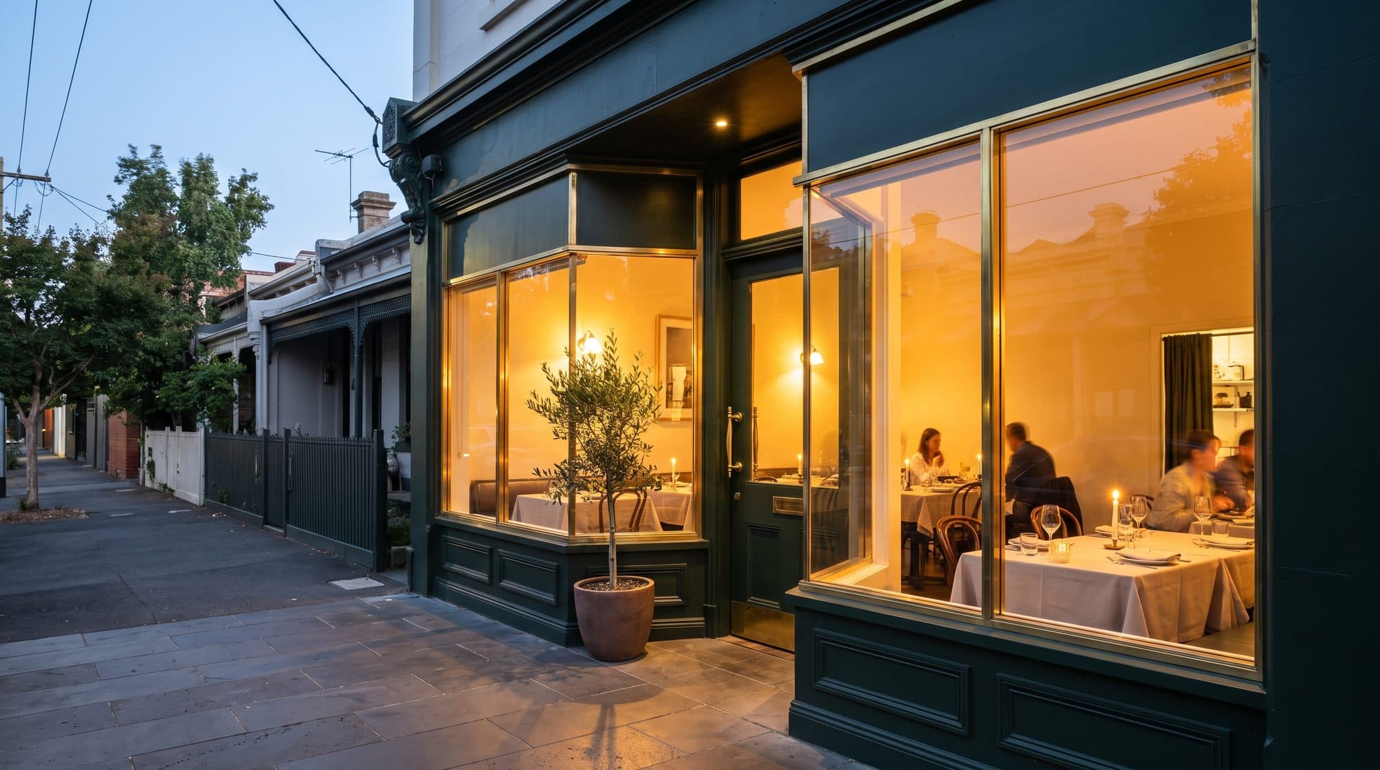 The restaurant shopfront at dusk, lit warmly from within